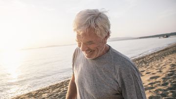 Hombre de mediana edad sonriendo dando un paseo por la playa