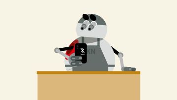 Irudian, bola formako robot bat ageri da, mugikor bati begira, mostradore baten atzean.