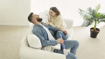 Una pareja sentada en un sofá blanco riéndose