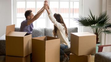 Una pareja en su casa chocando los cinco rodeados de cajas