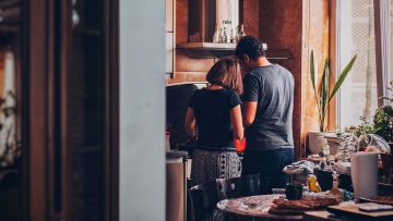 Pareja de espaldas en una cocina de colores marrones