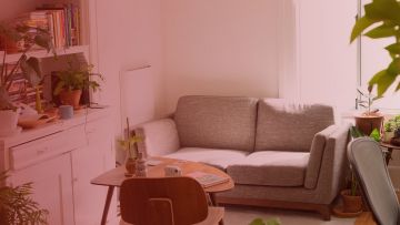 Landarez inguratuta dagoen sofa eta mahai bat dituen etxe bateko txoko baten irudia.