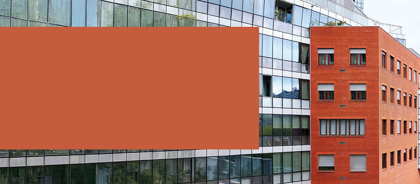 Edificio de viviendas que combina fachada de ladrillo rojo y cristal, con persianas en algunas ventanas.